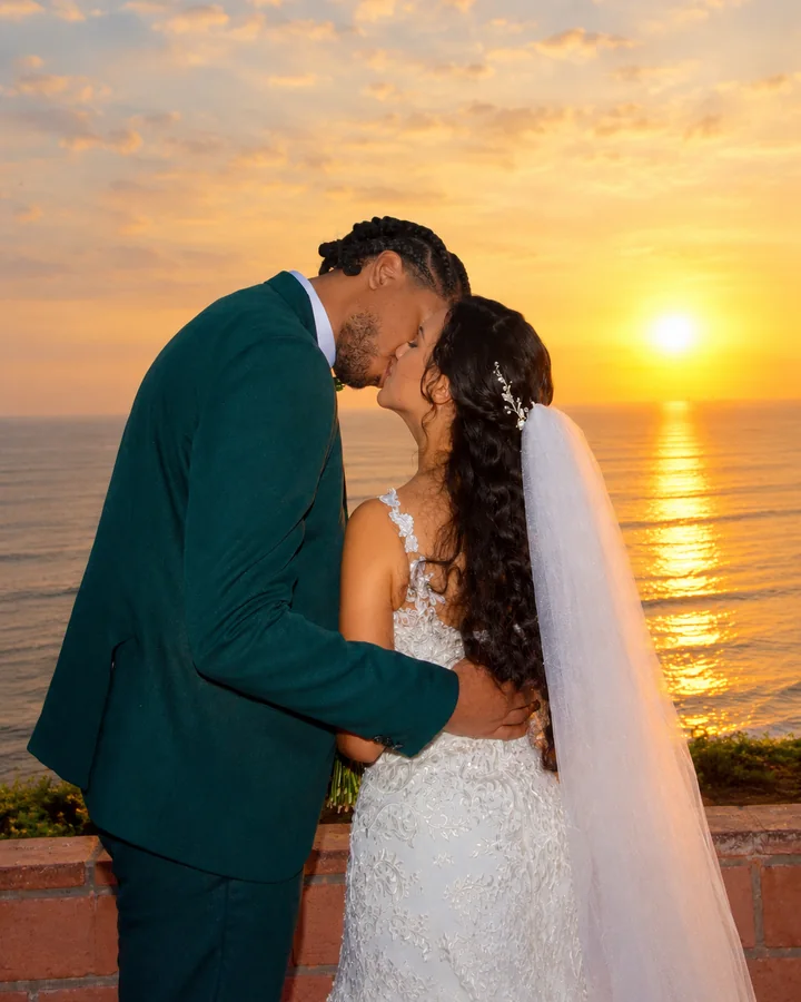 Novios besándose frente al mar durante el atardecer